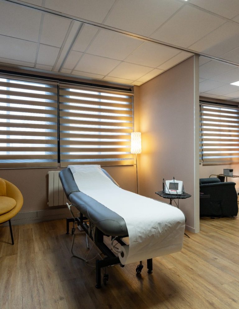 - Cabinet Hypnose et Luxopuncture Reims Salle de consultation avec un lit d'examen, une chaise et des fenêtres à lamelles.