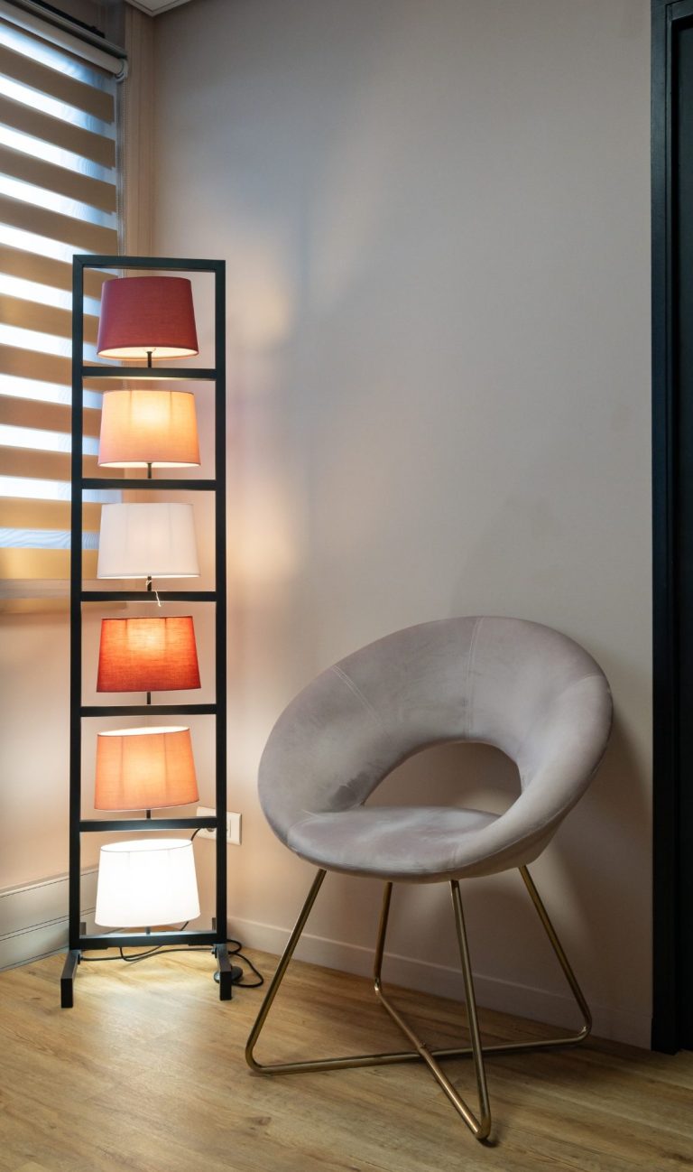 Cabinet Hypnose et Luxopuncture Reims Lamp à bandes colorées à côté d'un fauteuil doux dans un coin de pièce.